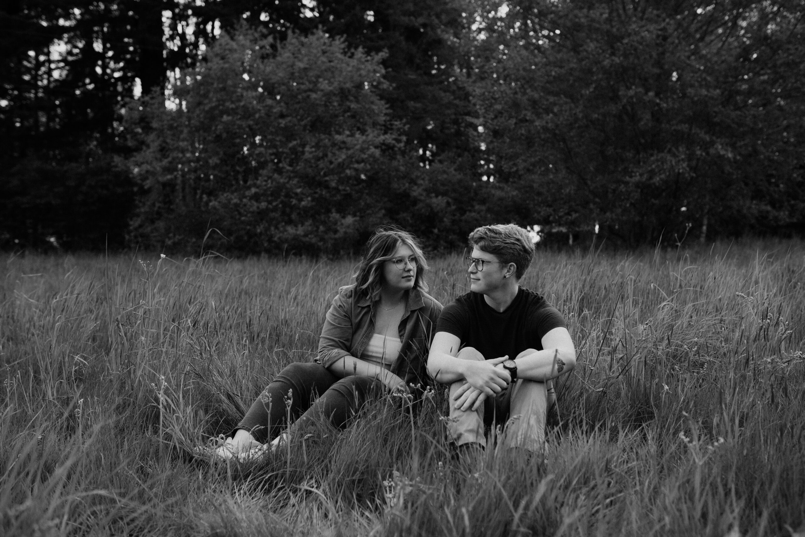 boy and girl sitting in a field during bellingham engagement session