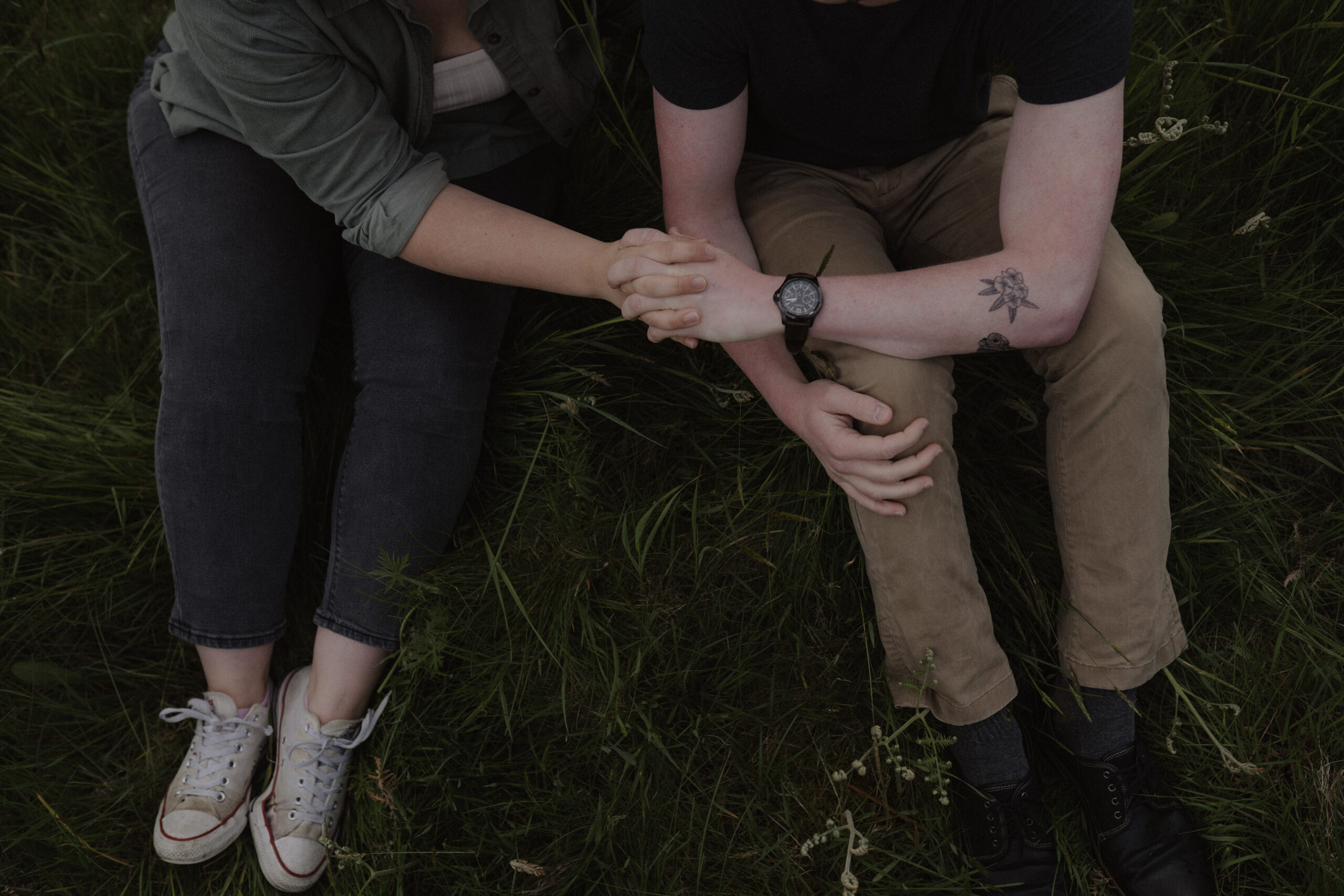 boy and girl hold hands in a field during bellingham engagement shoot