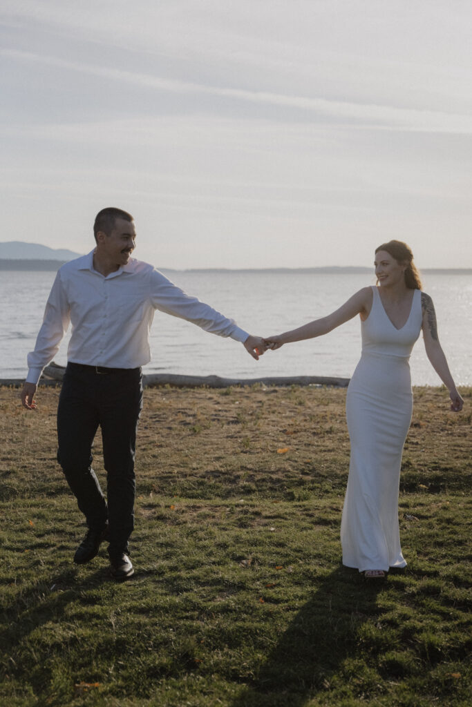 bride and groom hold hands and walk on beach