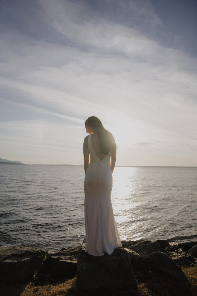 groom and bride stand on ocean rocks staring into ocean during Bellingham engagement shoot