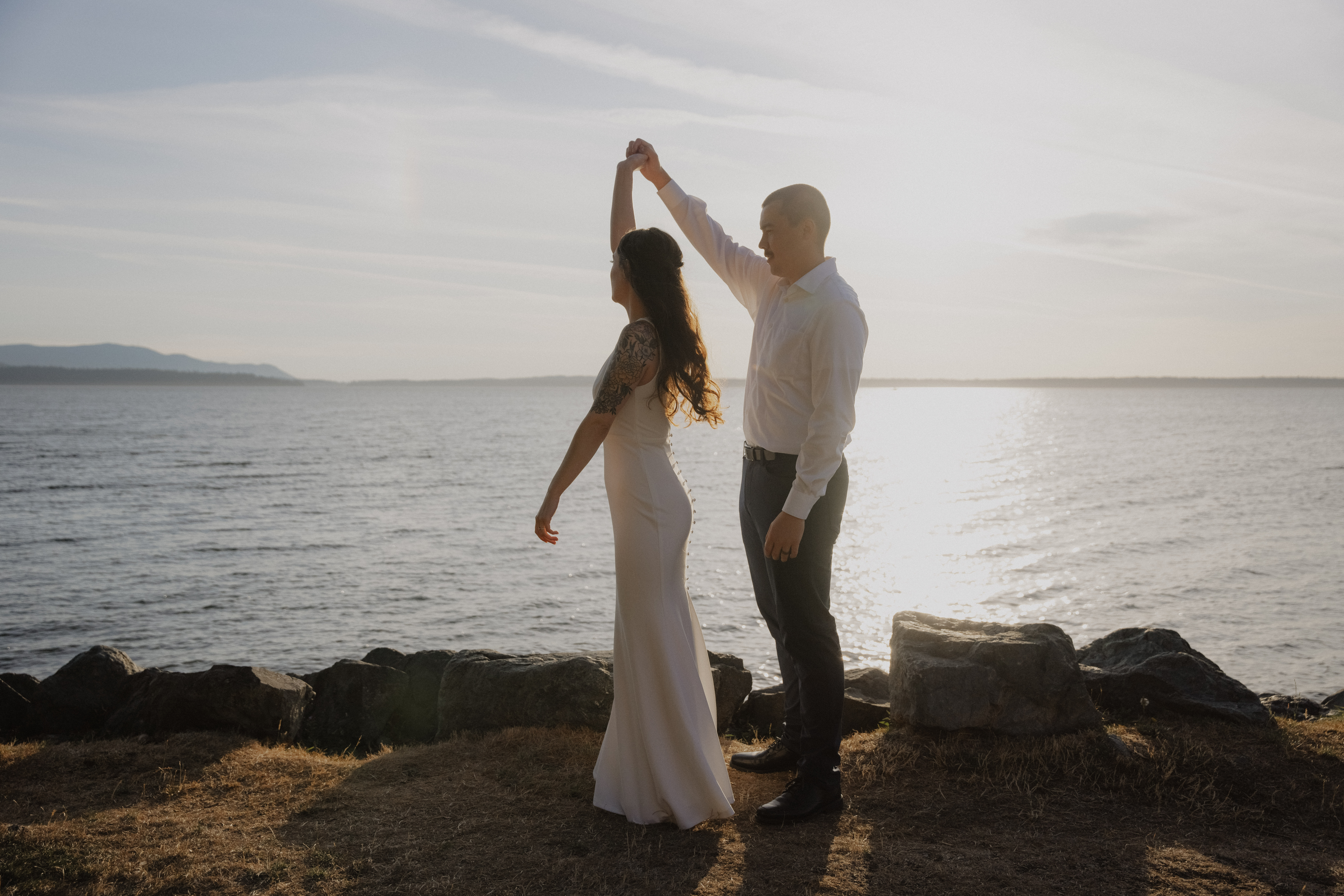 groom spins bride in front of the ocean