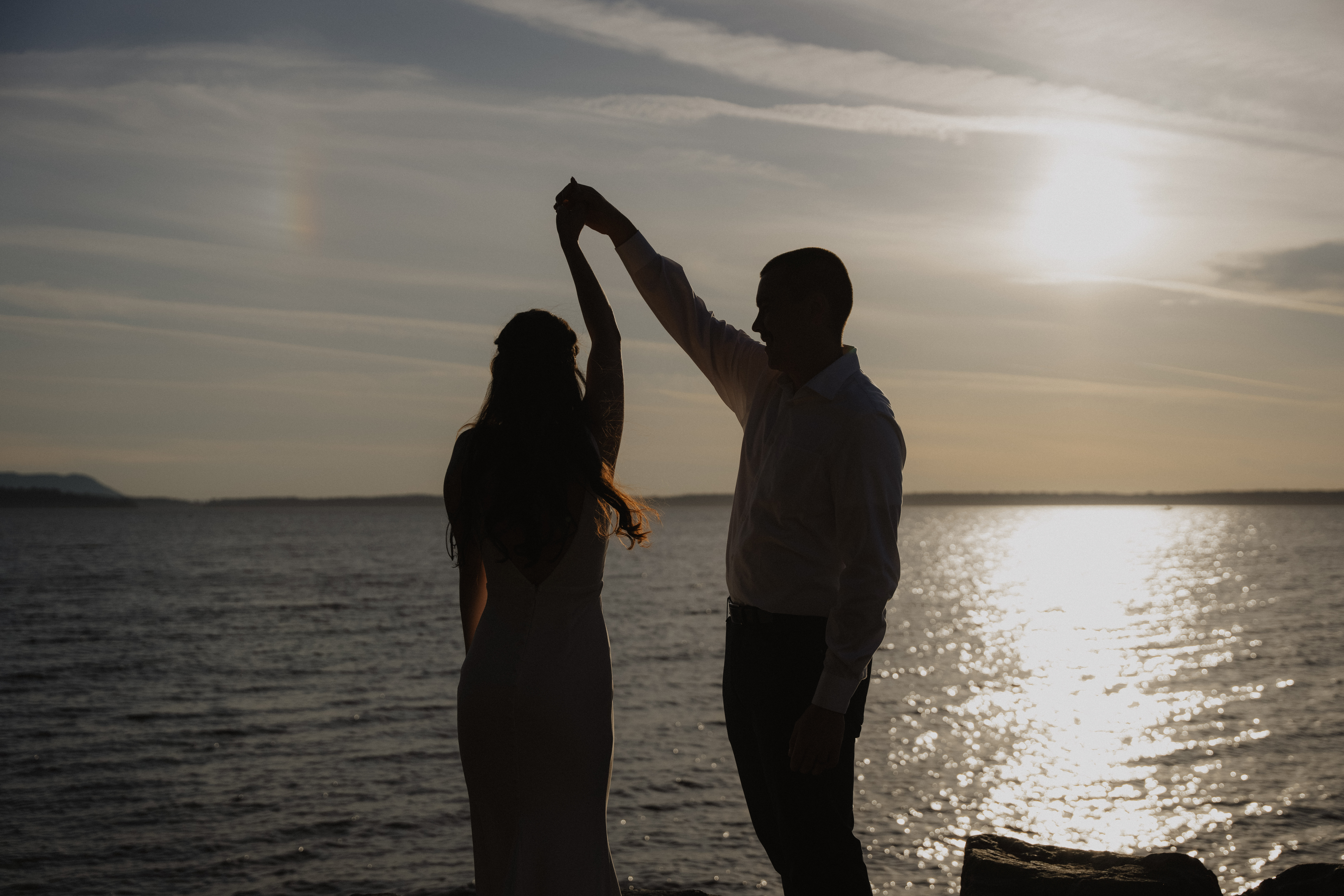 groom spins bride in front of the ocean