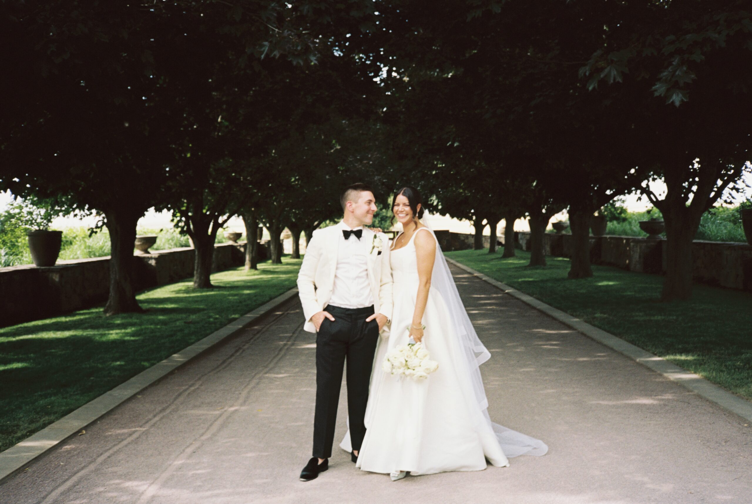bride and groom pose in driveway of Abeja winery