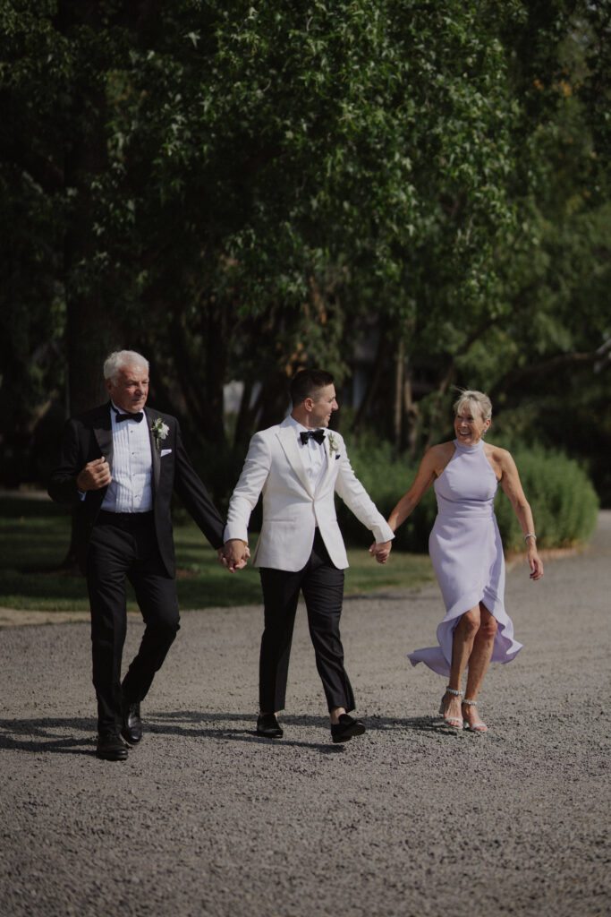 groom walks down aisle with mom and dad